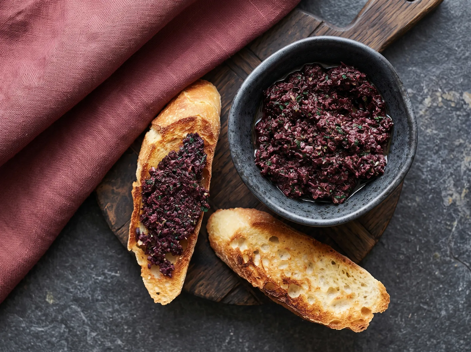 Tapenade noire — auf einem Brett angerichtet